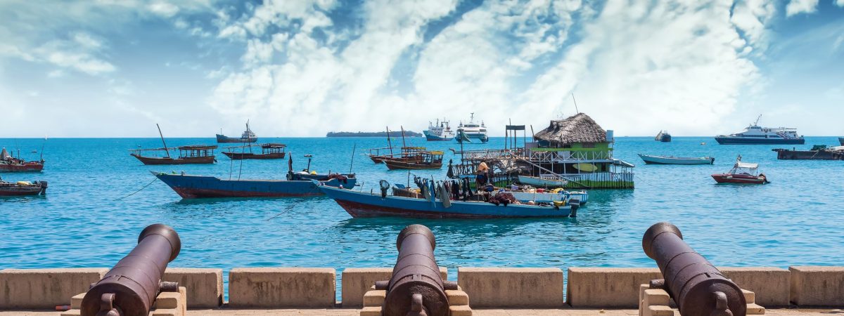 embankment with guns in Zanzibar Stone Town with boats in ocean and sky on the background